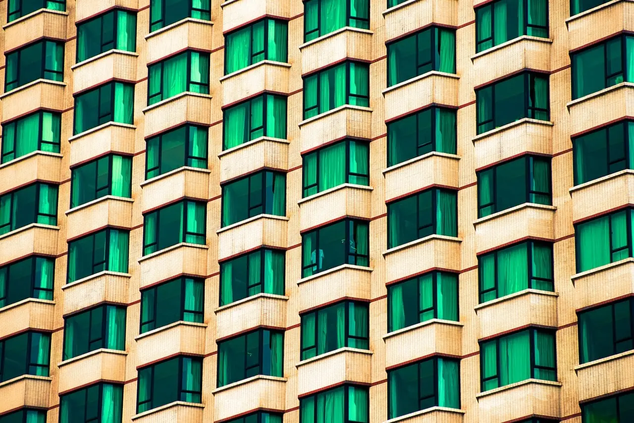 Façade d'immeuble moderne aux fenêtres vertes alignées en quadrillage